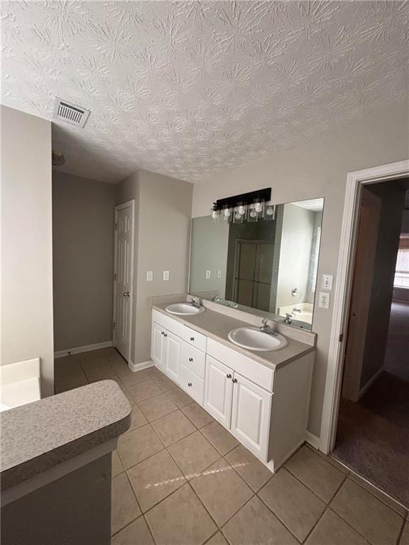 full bathroom featuring double vanity, tile patterned flooring, visible vents, and a sink