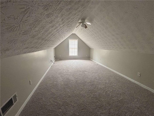 bonus room with baseboards, visible vents, lofted ceiling, carpet, and a textured ceiling