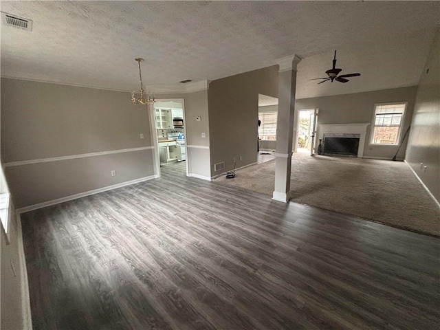 unfurnished living room with a fireplace with raised hearth, a textured ceiling, ceiling fan with notable chandelier, and visible vents