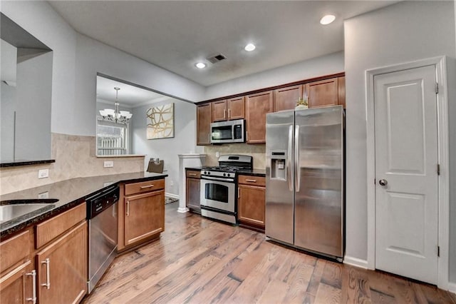 3351 Vintage Cir SE, Smyrna, GA 30080 - kitchen featuring stainless steel appliances, light wood-style floors, decorative backsplash, a chandelier, and dark stone countertops