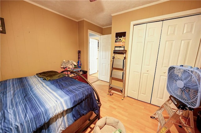 bedroom with a closet, a textured ceiling, ornamental molding, and light wood finished floors