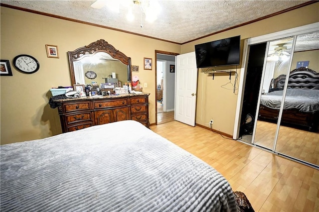 bedroom with a ceiling fan, light wood-style floors, multiple closets, a textured ceiling, and crown molding