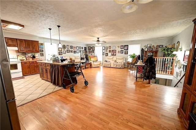 kitchen with white range with electric stovetop, open floor plan, light wood-type flooring, and a ceiling fan