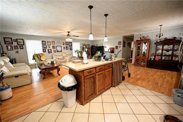 kitchen with light tile patterned floors, open floor plan, brown cabinets, and light countertops