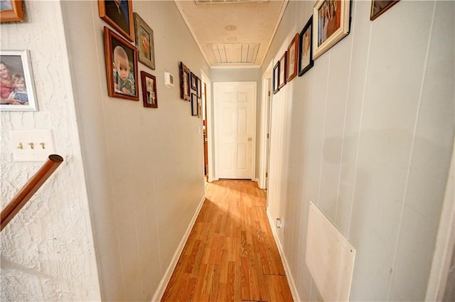 hallway with visible vents, baseboards, attic access, and light wood finished floors