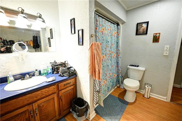 full bathroom featuring toilet, vanity, a textured wall, and wood finished floors