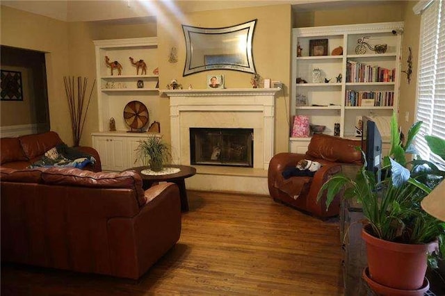 living area with a fireplace with raised hearth and wood finished floors