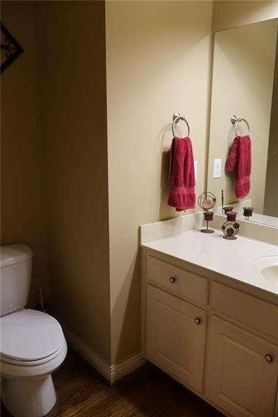 half bath featuring vanity, toilet, and wood finished floors