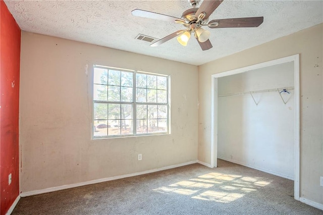 unfurnished bedroom with a textured ceiling, a closet, carpet flooring, and visible vents