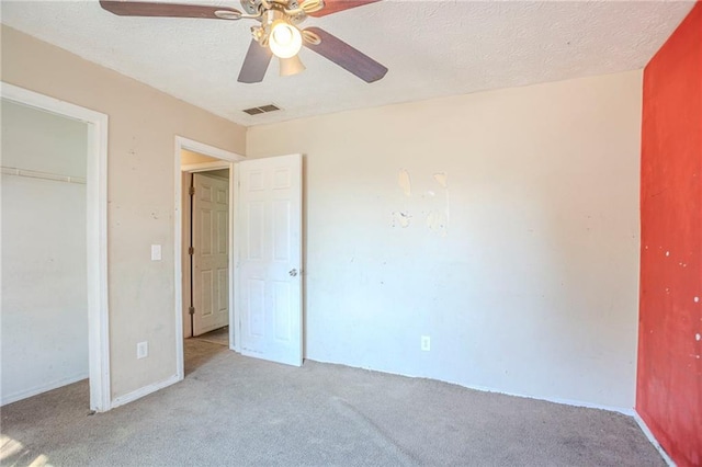 unfurnished bedroom with light carpet, visible vents, a ceiling fan, a textured ceiling, and a closet