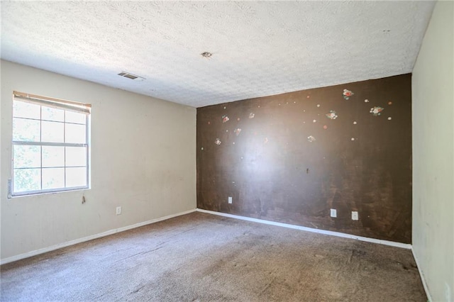 carpeted spare room featuring visible vents, a textured ceiling, and baseboards