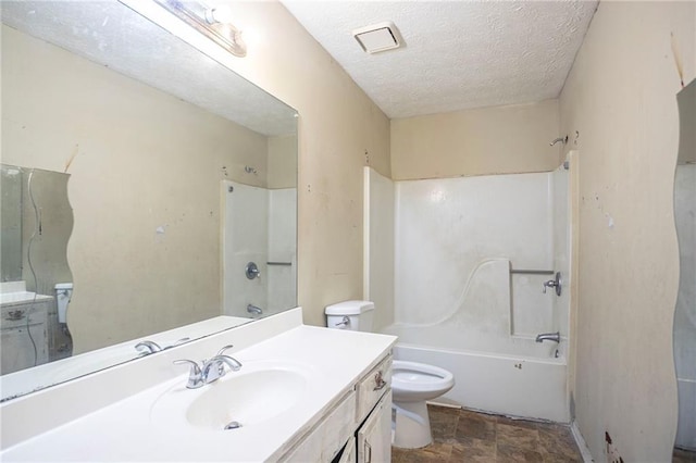 full bath featuring toilet, stone finish flooring, a textured ceiling, vanity, and shower / washtub combination