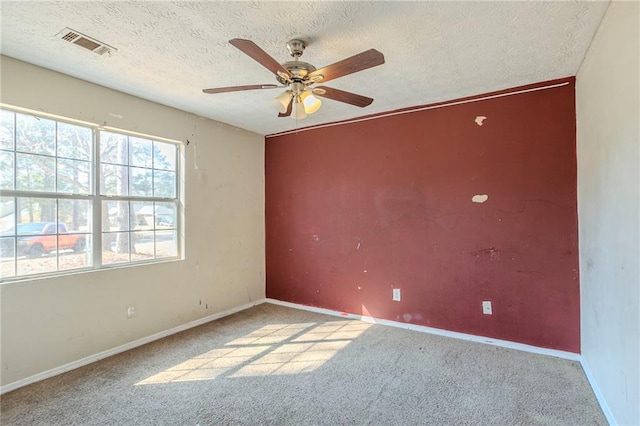 carpeted spare room featuring visible vents, ceiling fan, a textured ceiling, and baseboards