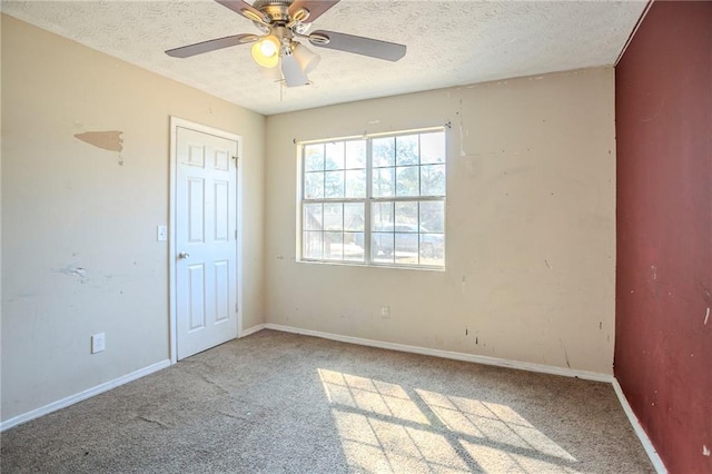 carpeted spare room with a ceiling fan, baseboards, and a textured ceiling