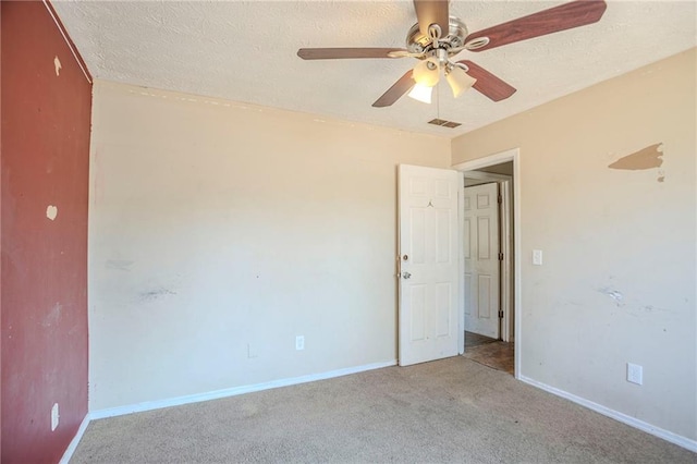 unfurnished room with carpet floors, baseboards, visible vents, and a textured ceiling