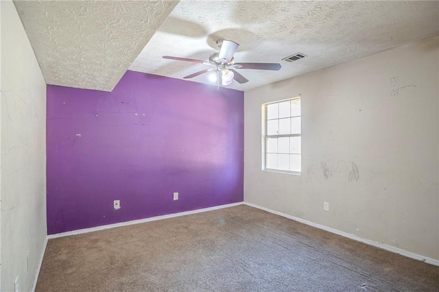 carpeted spare room featuring a textured ceiling, baseboards, visible vents, and a ceiling fan