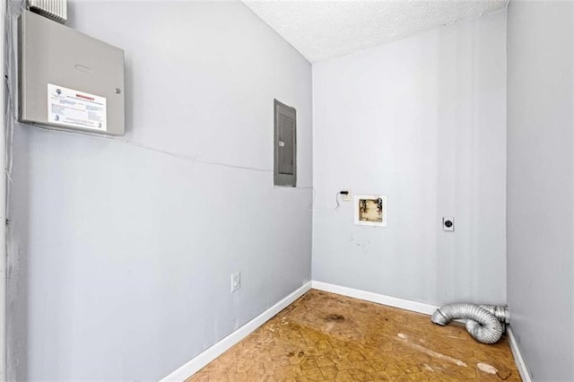 clothes washing area featuring electric panel, hookup for a washing machine, a textured ceiling, and hookup for an electric dryer