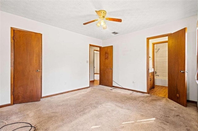 unfurnished bedroom with a textured ceiling, light colored carpet, ceiling fan, and ensuite bathroom