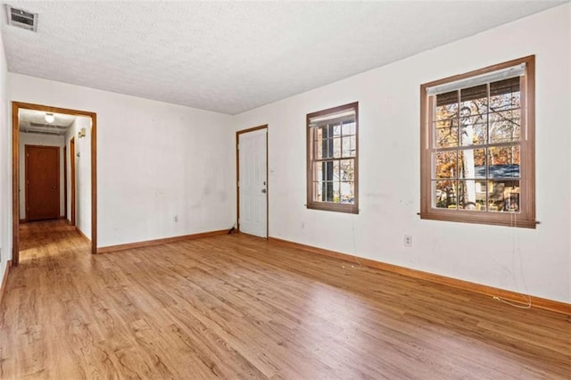 spare room with a textured ceiling and light hardwood / wood-style flooring