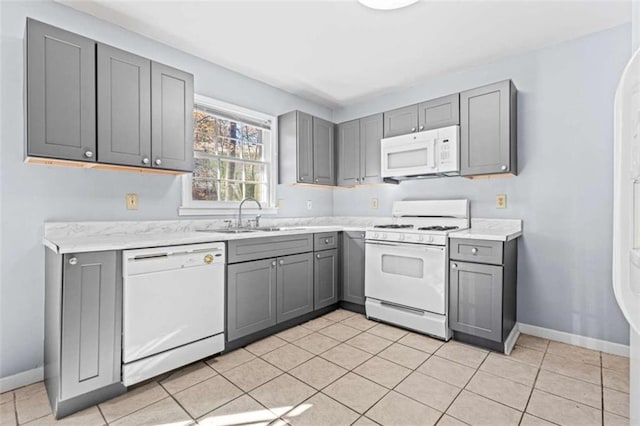 kitchen featuring light tile patterned floors, white appliances, gray cabinetry, and sink