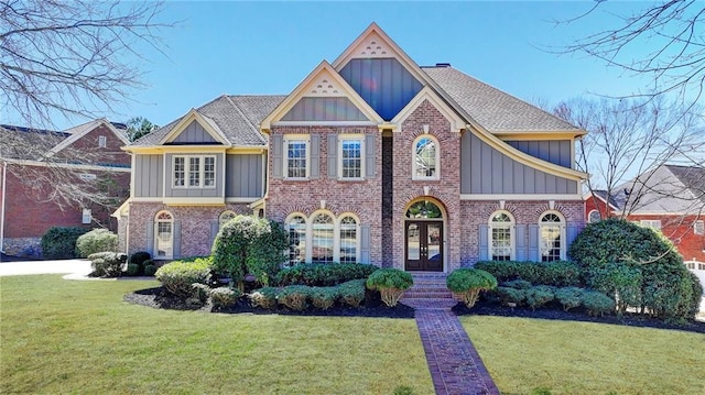 view of front of home with french doors, brick siding, roof with shingles, board and batten siding, and a front yard