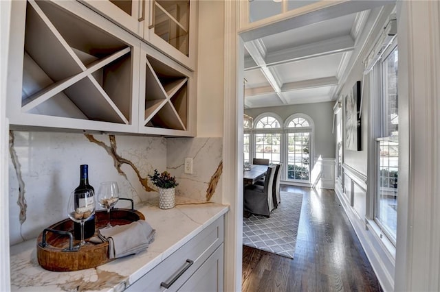 bar with dark wood finished floors, coffered ceiling, beamed ceiling, crown molding, and backsplash