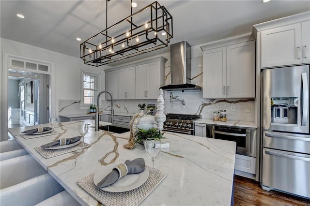 kitchen with stainless steel appliances, a sink, wall chimney range hood, and tasteful backsplash