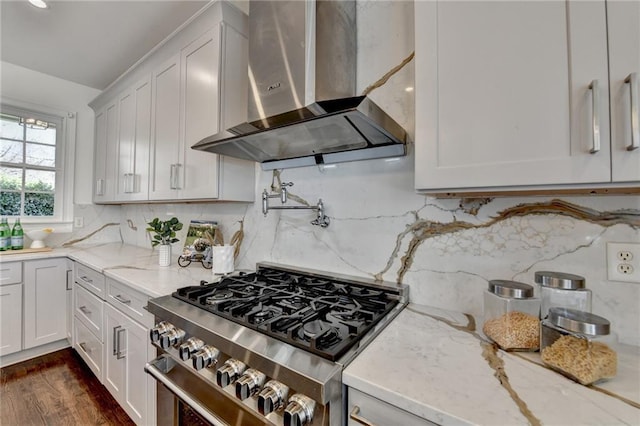 kitchen with stainless steel gas range, white cabinetry, wall chimney exhaust hood, and light stone countertops