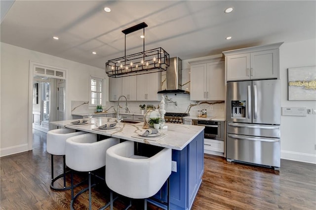 kitchen with decorative backsplash, wall chimney exhaust hood, light stone counters, dark wood-type flooring, and stainless steel appliances