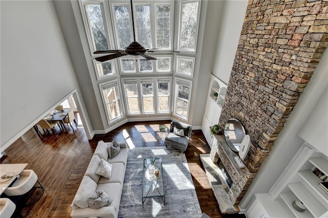 living area featuring dark wood-style floors, a fireplace, and a towering ceiling