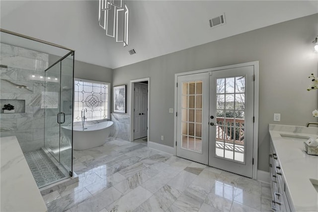 bathroom with marble finish floor, french doors, a wealth of natural light, visible vents, and a freestanding tub