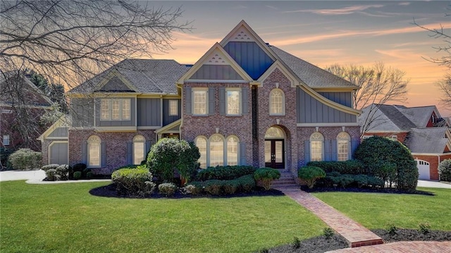 view of front facade with board and batten siding, brick siding, and a lawn