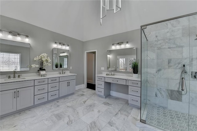 full bath featuring double vanity, a stall shower, marble finish floor, and a sink