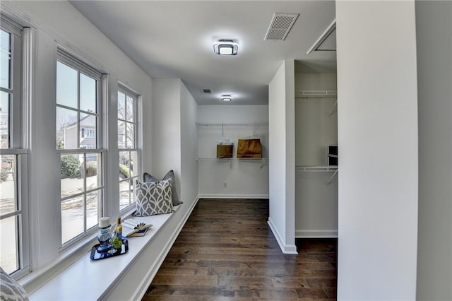 hallway with wood finished floors, visible vents, and baseboards