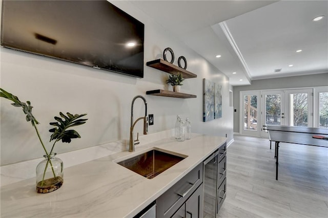 kitchen featuring crown molding, light stone counters, open shelves, and a sink