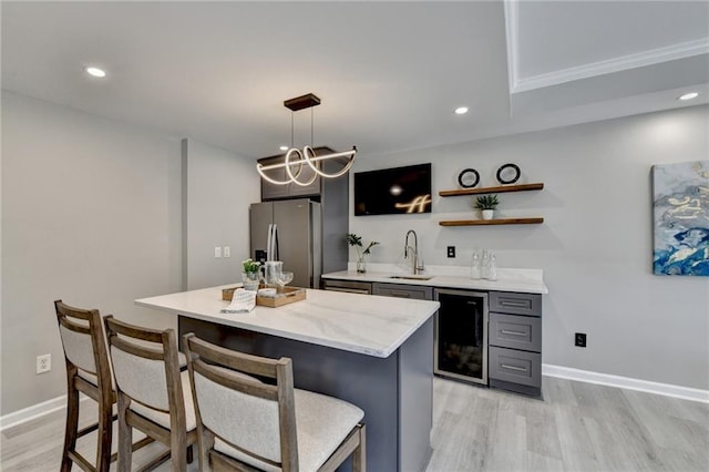 bar with beverage cooler, light wood finished floors, a sink, and stainless steel fridge