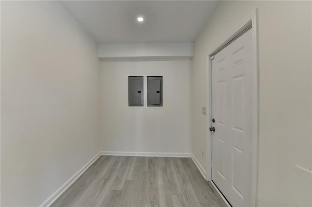 doorway with light wood-type flooring, electric panel, and baseboards