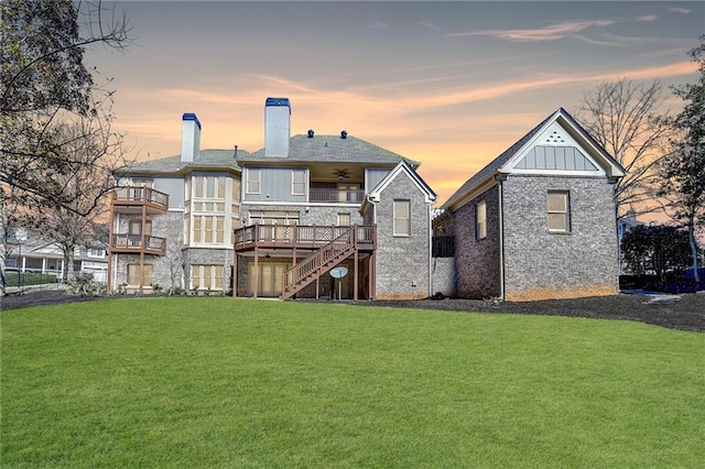 back of house at dusk with a yard, a chimney, board and batten siding, ceiling fan, and stairs