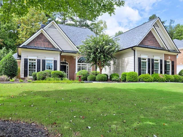 craftsman inspired home with brick siding, roof with shingles, and a front yard