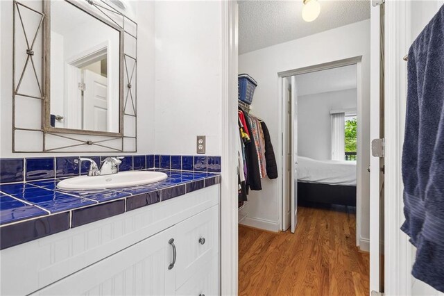 bathroom with vanity, a textured ceiling, and wood finished floors