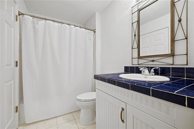 full bath featuring vanity, a textured ceiling, shower / tub combo, and toilet