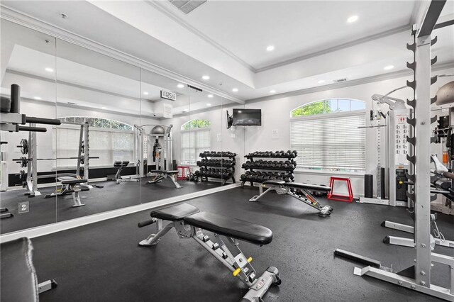 exercise room featuring crown molding, recessed lighting, a raised ceiling, and a healthy amount of sunlight