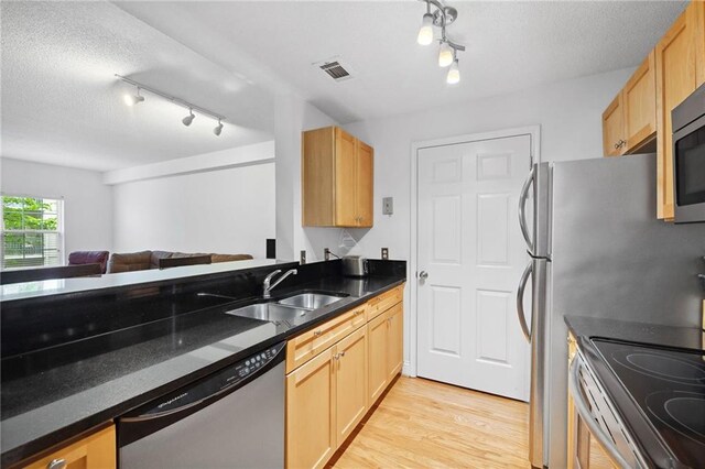 kitchen with light wood-type flooring, rail lighting, a sink, and appliances with stainless steel finishes