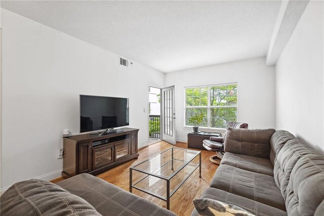 living room with baseboards, visible vents, and light wood finished floors