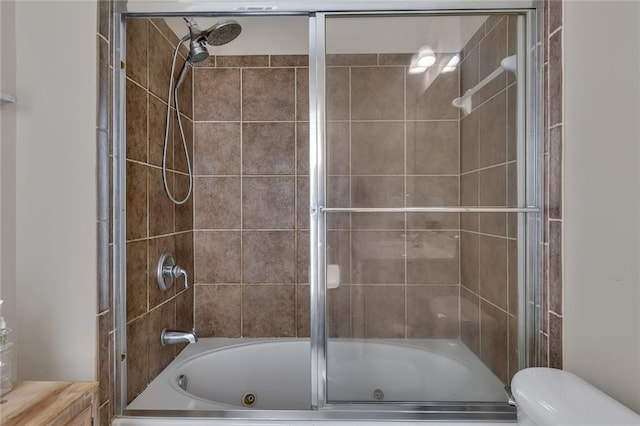 bathroom featuring combined bath / shower with glass door and toilet