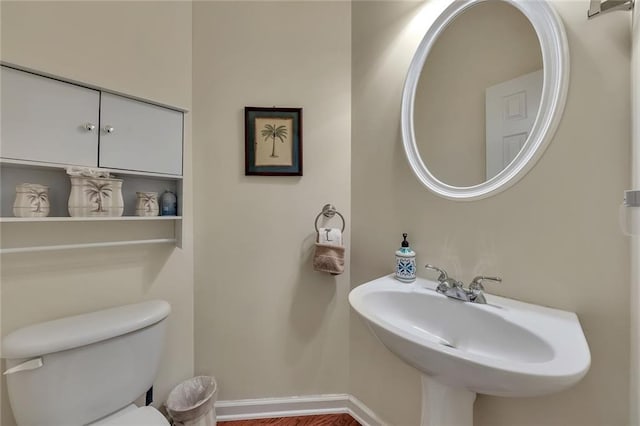 half bathroom with a sink, toilet, and baseboards