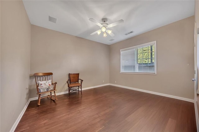 living area with dark wood-style floors, visible vents, baseboards, and a ceiling fan