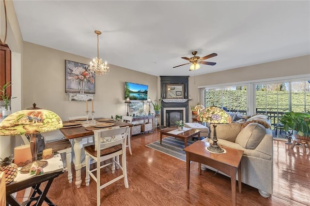 living area featuring ceiling fan with notable chandelier, a fireplace, and wood finished floors