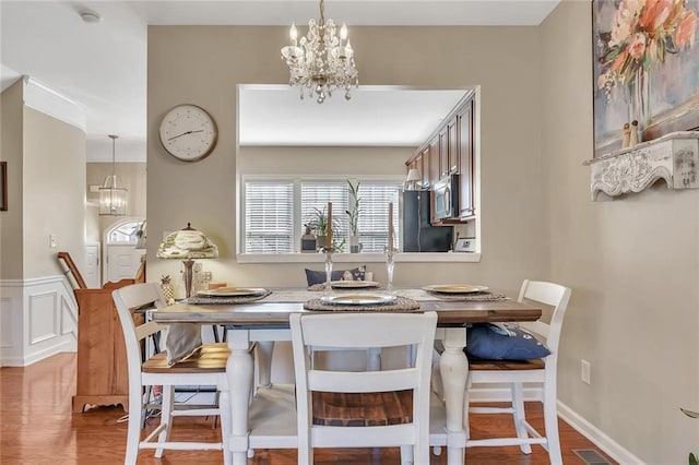 dining room with baseboards, visible vents, a notable chandelier, and wood finished floors