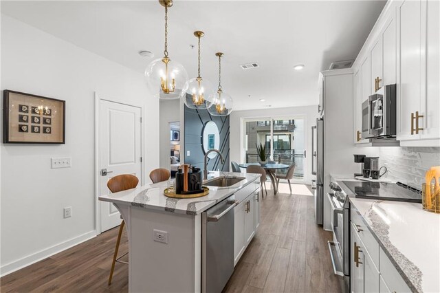 kitchen with white cabinets, an island with sink, sink, stainless steel appliances, and dark hardwood / wood-style flooring